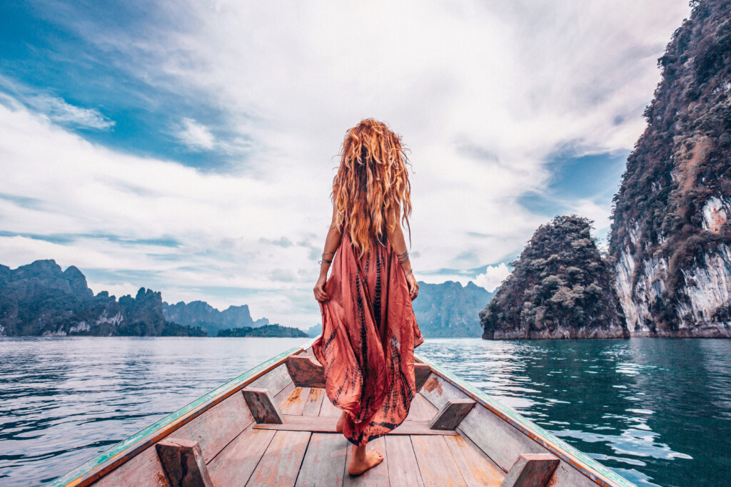 fashionable young model in boho style dress on boat at the lake